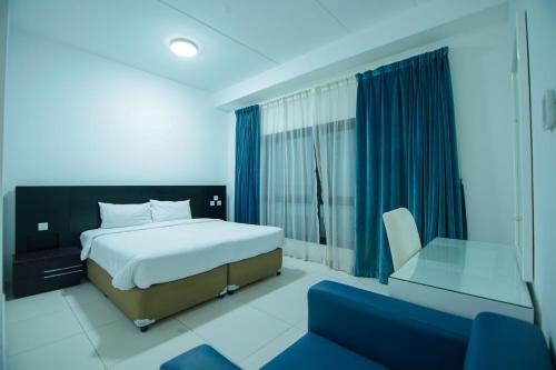 een slaapkamer met een bed, een stoel en een raam bij Home Away Holiday Homes in Dubai