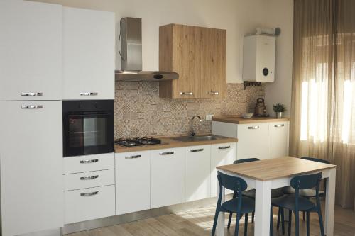 桑格羅堡的住宿－Appartamento Felicia，厨房配有白色橱柜和桌椅
