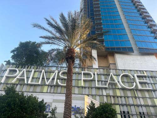 a palm tree in front of a building with a large sign at Amazing view 18th floor at Palms place Las Vegas in Las Vegas