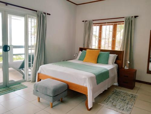 a bedroom with a bed and a chair and windows at Roz A Mer - Beach Apartment in Mahe