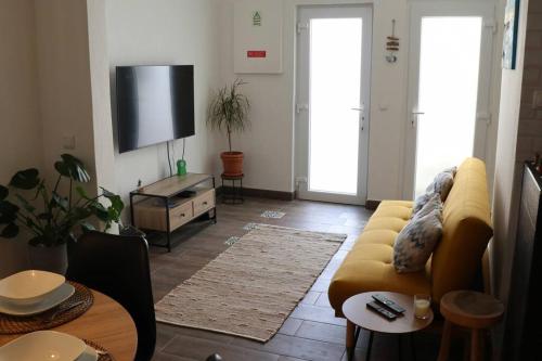 a living room with a yellow couch and a tv at Casa Vento Budens in Budens