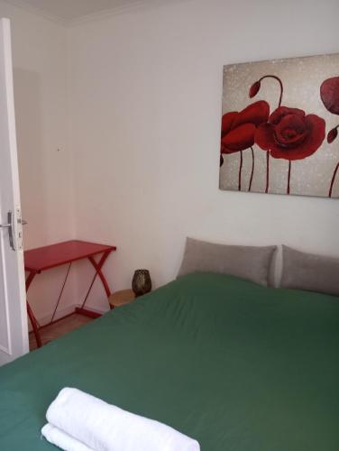 Un dormitorio con una cama verde con una pintura de flores rojas en Chambre cour, en Fontaine