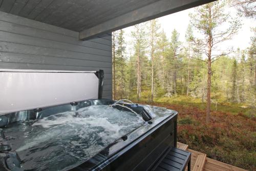 a hot tub on a deck with a view of the woods at Villa Kanger Ruka 2 in Kuusamo
