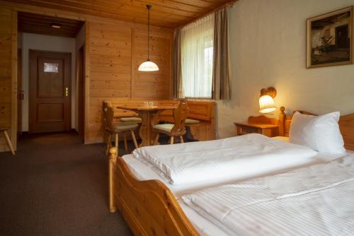 a bedroom with a bed and a table and chairs at Seehotel Weissensee in Füssen