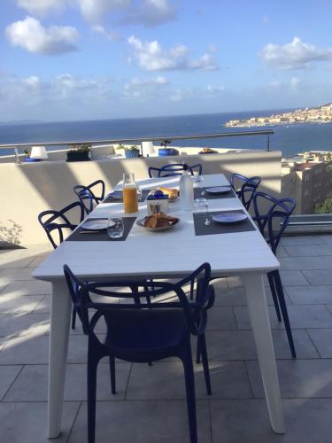 una mesa blanca y sillas en la parte superior de un balcón en Suite avec 2 chambres d'hôtes pour 1 à 4 personnes avec terrasse, vue mer, parking privé, proche port et aéroport, en Ajaccio