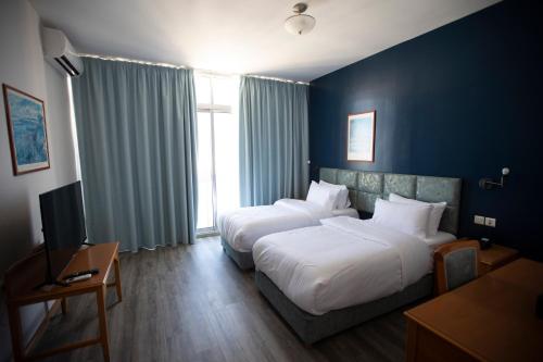 a hotel room with two beds and a television at El Sheikh Suites Hotel in Beirut