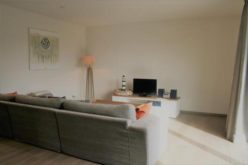 een woonkamer met een bank en een televisie bij Strandhuis 0102 in De Haan