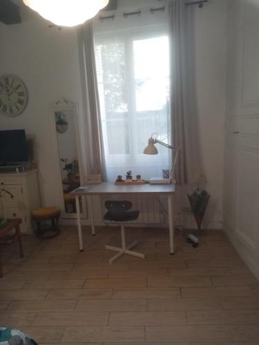een bureau met een lamp in een kamer met een raam bij les amandiers in Tours