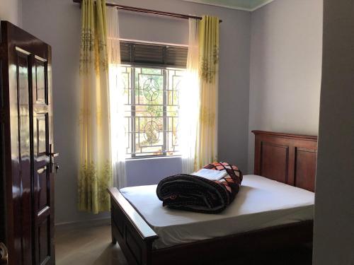 ein Schlafzimmer mit einem Bett mit einer Tasche darauf in der Unterkunft Fort Marigold Hotel in Fort Portal