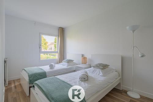 2 bedden in een witte kamer met een raam bij R 'AppartsT3 Serenity Haven in Torcy