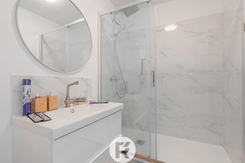 een badkamer met een wastafel en een douche met een spiegel bij R 'AppartsT3 Serenity Haven in Torcy