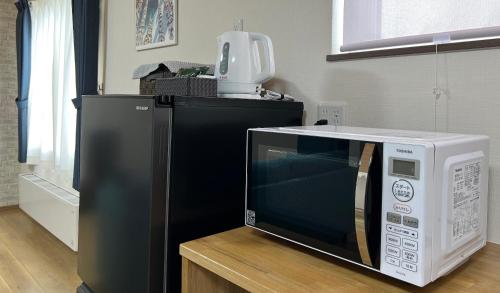 a microwave oven sitting on top of a table at Furano Yukisachi House in Furano