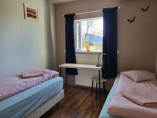 HvanneyriにあるHvanneyri apartmentのベッド2台、デスク、窓が備わる客室です。