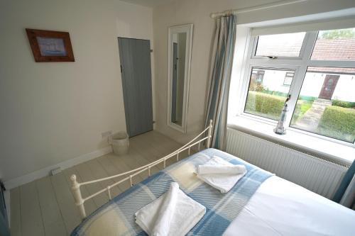 een bed in een kamer met een raam en een bed sidx sidx sidx bij Cranny Cottage Carnlough in Carnlough