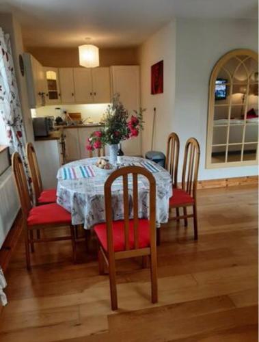 a dining room table with red cushioned chairs and a kitchen at The Lake House Apartment in Drumshanbo