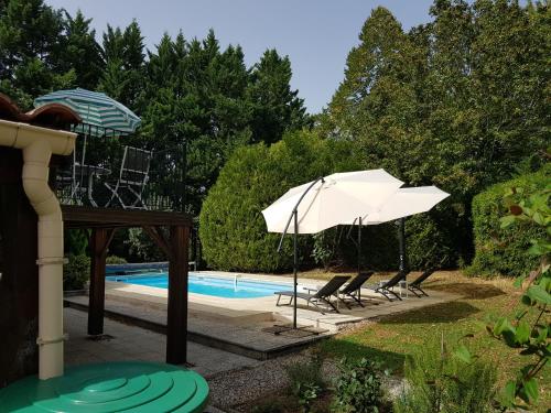 a swimming pool with two chairs and an umbrella at Superb contemporary 3 bed villa in Cancon