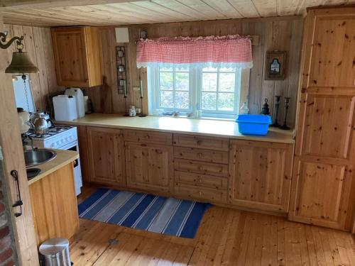 een grote keuken met houten kasten en een raam bij Svingom - hytte uten strøm og vann 