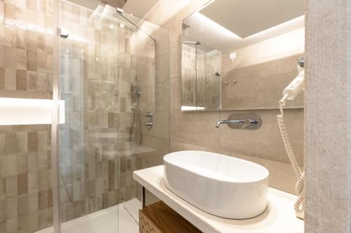 a bathroom with a white sink and a shower at Hotel Club Saraceno - Bovis Hotels in Àrbatax