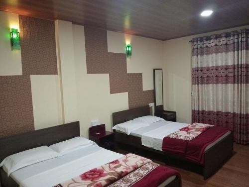 ein Hotelzimmer mit 2 Betten und einem Spiegel in der Unterkunft Thuvaraga Inn in Nuwara Eliya