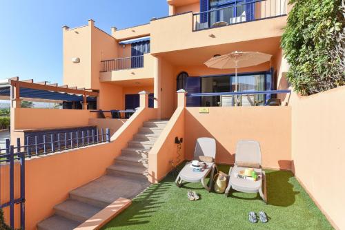 a house with two chairs and an umbrella at Meloneras Bahia 28 by VillaGranCanaria in Meloneras
