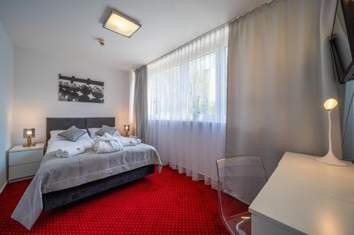 1 dormitorio con 1 cama y alfombra roja en Hotel Gromada Poznań en Poznan