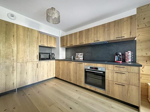 - une cuisine avec des placards en bois et une cuisinière dans l'établissement GRD005 - Appartement standing 6 pers pied de piste, aux Carroz d'Arâches