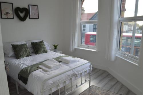 Cama blanca en habitación con 2 ventanas en Flat very close to Stratford!, en Londres