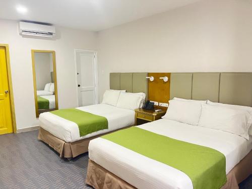 a hotel room with two beds with green and white at Hotel American Golf in Barranquilla