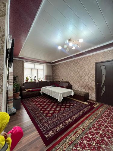 un soggiorno con tavolo e un grande tappeto di Jyrgal jashoo guest house 