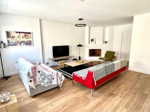 a living room with two couches and a tv at Superbe appartement avec parking in La Rochelle