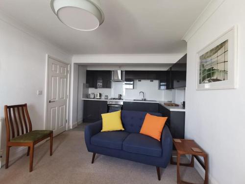 uma sala de estar com um sofá azul e uma cozinha em Relax and enjoy the sea view em Kent