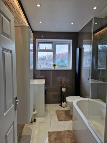 uma casa de banho com uma banheira, um WC e um lavatório. em Stylish 2 bed home- short walk to Tottenham Stadium/Stations em Londres