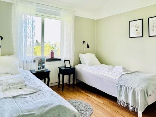 2 camas en una habitación blanca con ventana en Vadstena Folkhögskola Vandrarhem, en Vadstena
