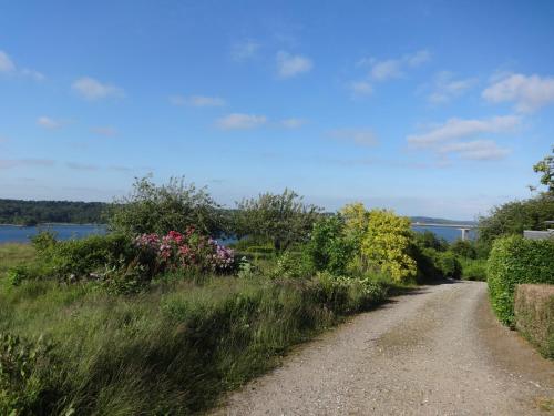 a dirt road with flowers and a bridge in the background at Casa Mundo Bed & Breakfast in Vejle