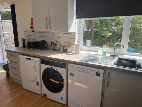 a kitchen with a washing machine and a sink at NEW-4 Bdrm-6 quality beds-2 full bathrm-1 bath-3 vehicle forecourt-washer-dryer-Biz WiFi in Corby