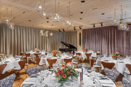 a ballroom with tables and chairs and a piano at Appenzeller Huus Löwen in Gonten