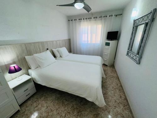 a white bedroom with a large bed and a mirror at Las Vistas Beach Los Cristianos 2 Swimming Pools in Los Cristianos