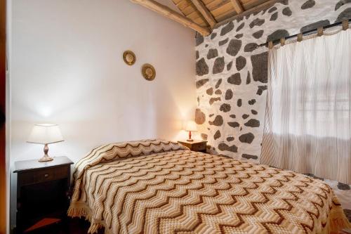 um quarto com uma cama e uma parede de pedra em Adega Maciel em Lajido