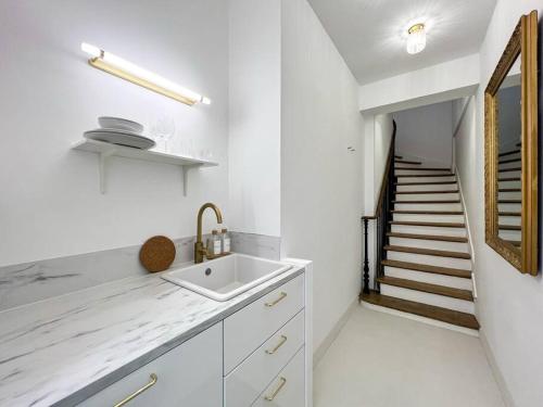 a white kitchen with a sink and a staircase at Charmant Studio Palais Royal Musée du Louvre in Paris