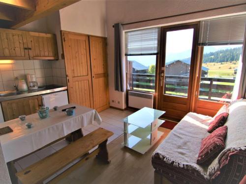 une cuisine et un salon avec une table et un canapé dans l'établissement Studio mezzanine ensoleillé aux Saisies, proche télésièges, balcon sud, animaux acceptés - FR-1-594-204, à Hauteluce