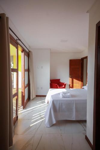 a bedroom with two beds and a red chair at Villa Botanic Garden in Itacaré