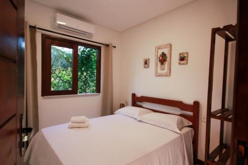 sypialnia z łóżkiem z białą pościelą i oknem w obiekcie Villa Botanic Garden w mieście Itacaré