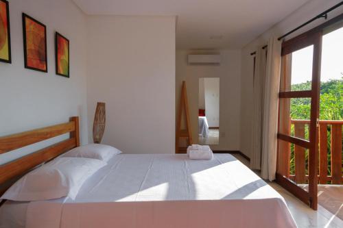 a bedroom with a large white bed and a balcony at Villa Botanic Garden in Itacaré