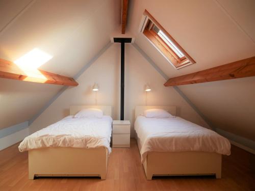 een slaapkamer op zolder met 2 bedden en een dakraam bij Nova Park V88 in De Haan