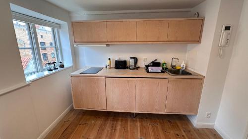 a kitchen with wooden cabinets and a sink and a window at Boutique Apartments 1 - 8 in Copenhagen