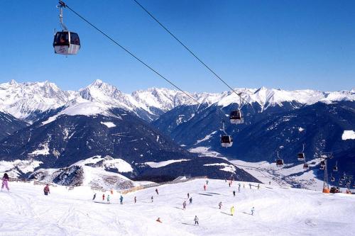 a group of people riding a ski lift on a snow covered mountain at Kronplatz Mountain Lodge in Brunico