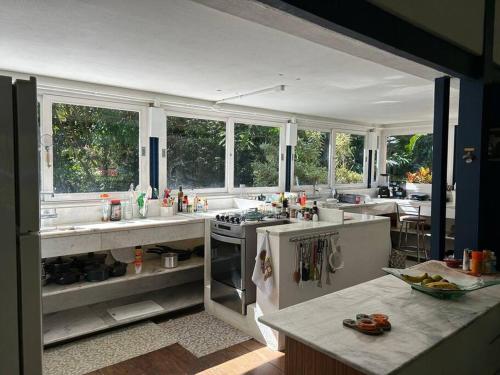 cocina grande con encimeras blancas y ventanas en Schönes Haus direkt am Fluß in der Mata Atlantica, en São Sebastião