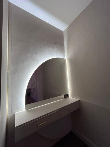 a bathroom with a mirror and a white wall at King Sky Tower Hotel in Batumi