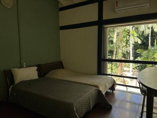 2 camas en una habitación con ventana y mesa en Schönes Haus direkt am Fluß in der Mata Atlantica, en São Sebastião