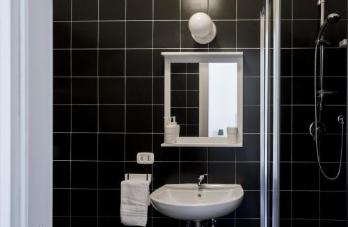 ein schwarz gefliestes Badezimmer mit Waschbecken und Spiegel in der Unterkunft Taggarb in Neapel